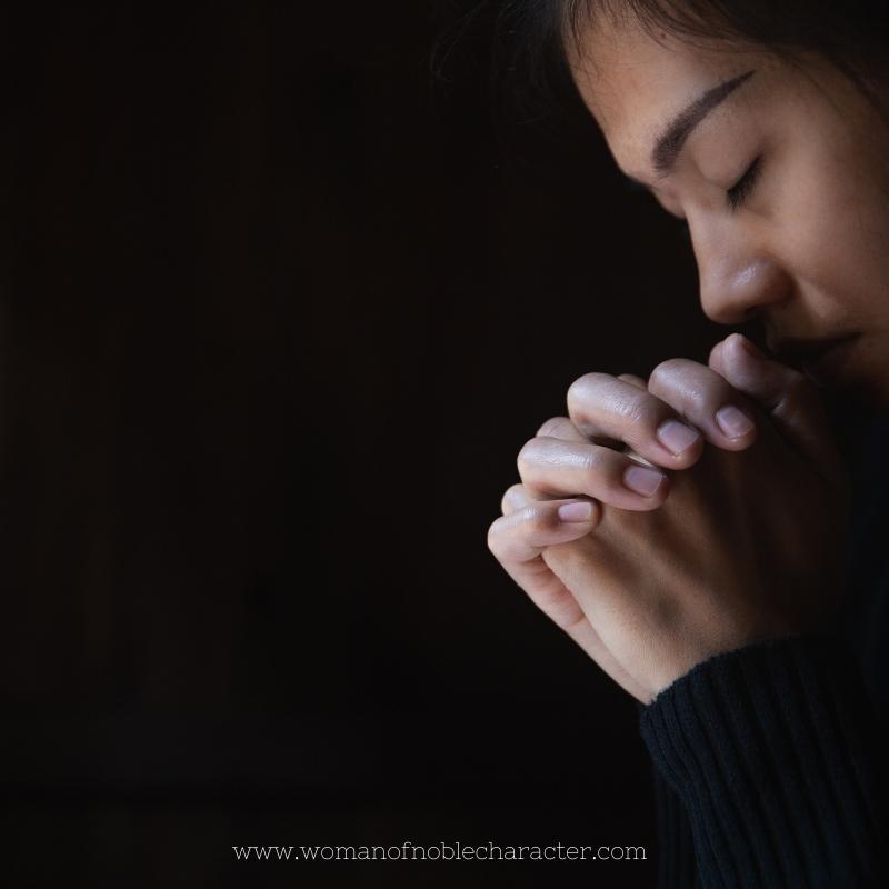 image of woman praying on dark background for the post When They See Me Do They See Jesus?