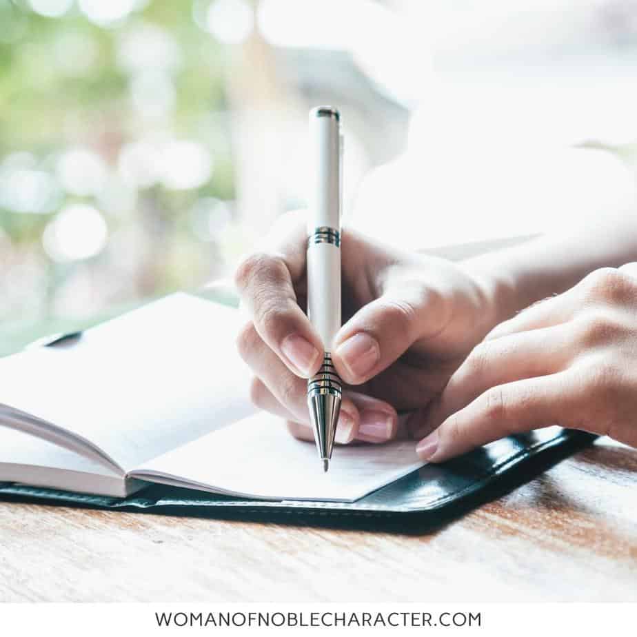 image of woman writing in journal on desk for the post How To Set Up A War Binder For Your Time With God