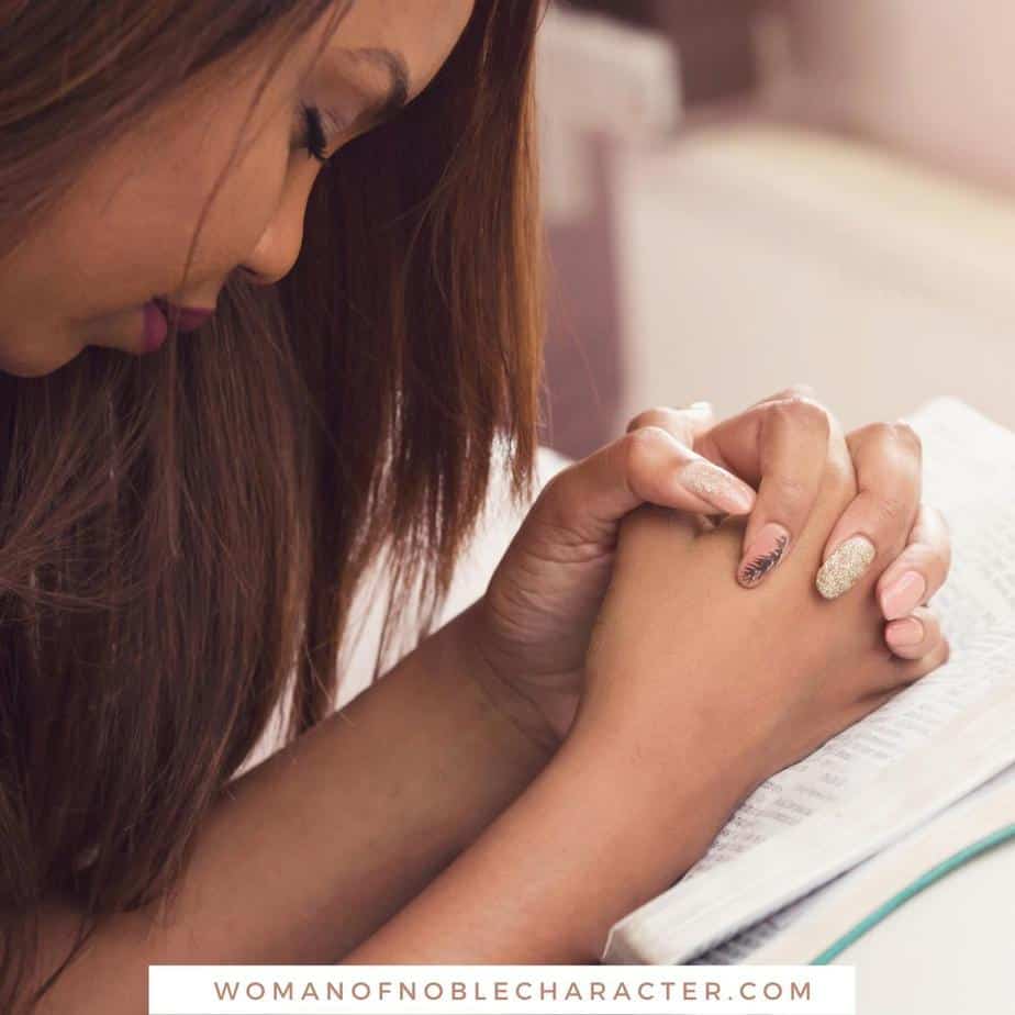 image of woman praying with hands clasped over Bible for the post 7 Prayers to Pray for Your Children