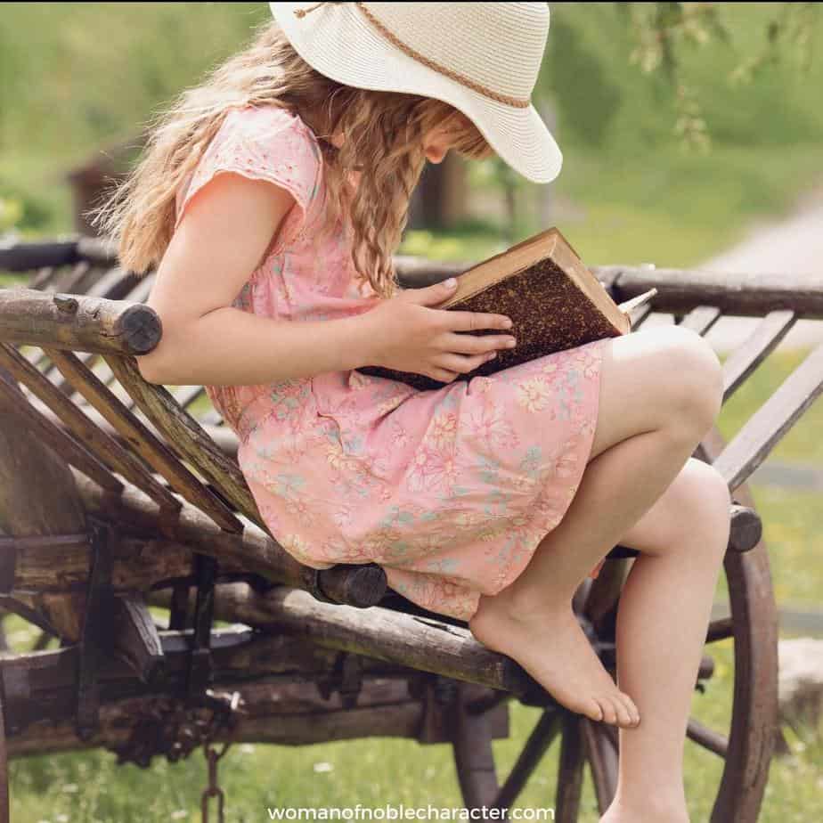image of little girl sitting on bench reading a Bible for the post Practical Ways To Teach Your Children About God At Every Age