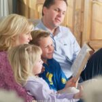 image of mother and father reading family devotions to young boy and girl for the post Three Benefits of Family Devotions, 11 Tips and Top Family Devotion Books