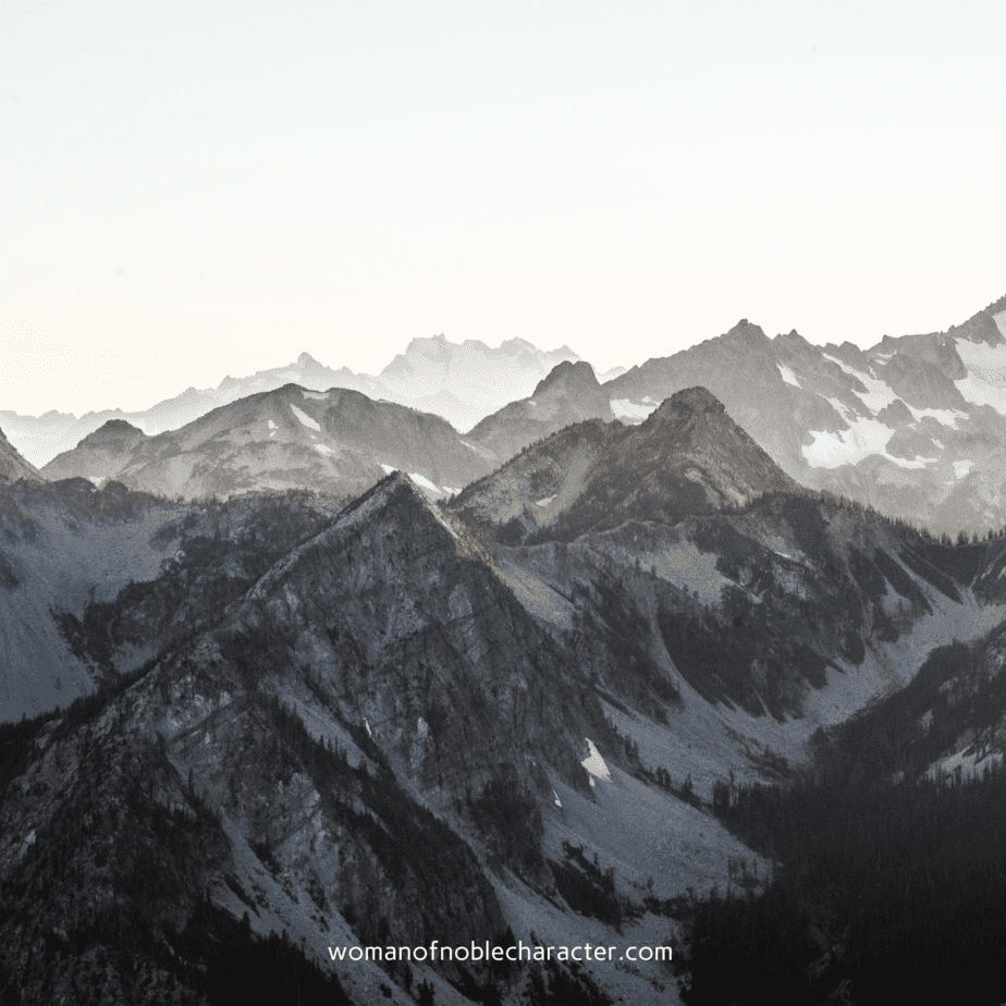 image of black and grey mountains for the post image of mountains and valleys with cloud covering with the text The Beautiful Significance of Mountains in the Bible and in Life & a Look at Valleys in the Bible