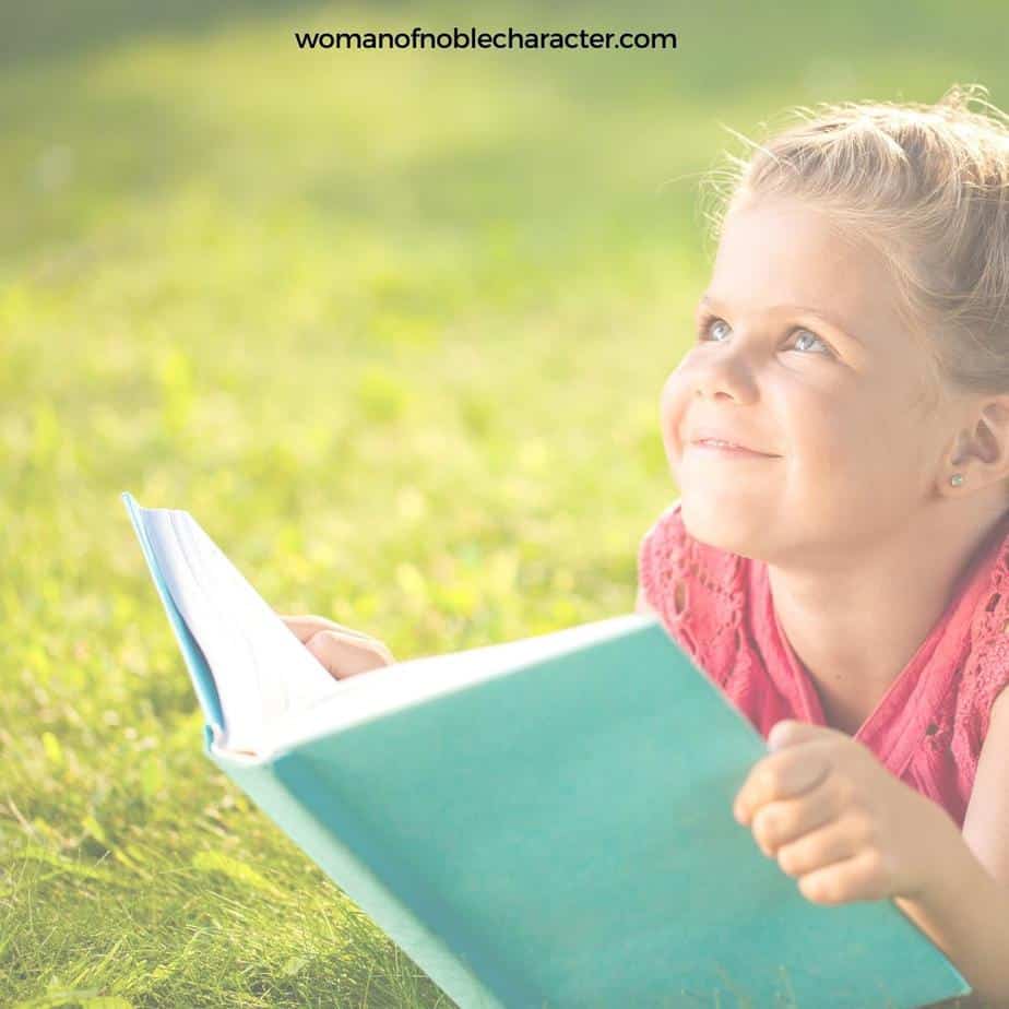 image of girl with open Bible laying on grass for the post 25 Bible Verses for Children to Memorize