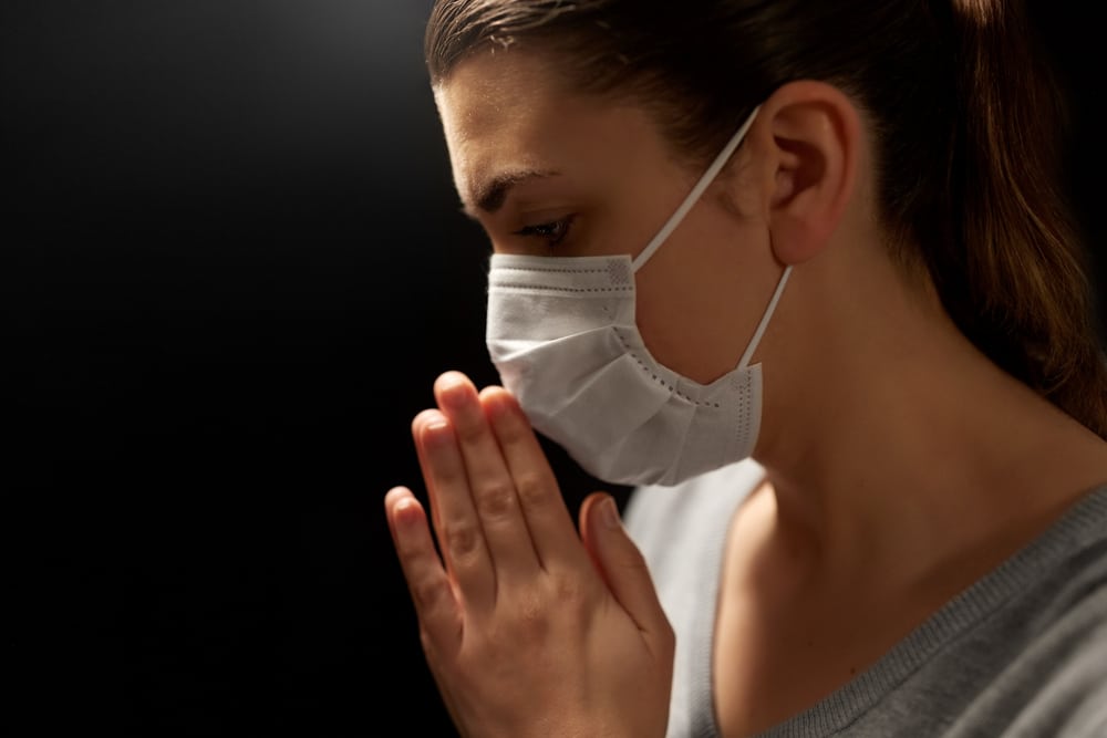 health protection, safety and pandemic concept - close up of sick young woman in protective medical face mask praying over black background;  people prayed for me and my cancer treatment