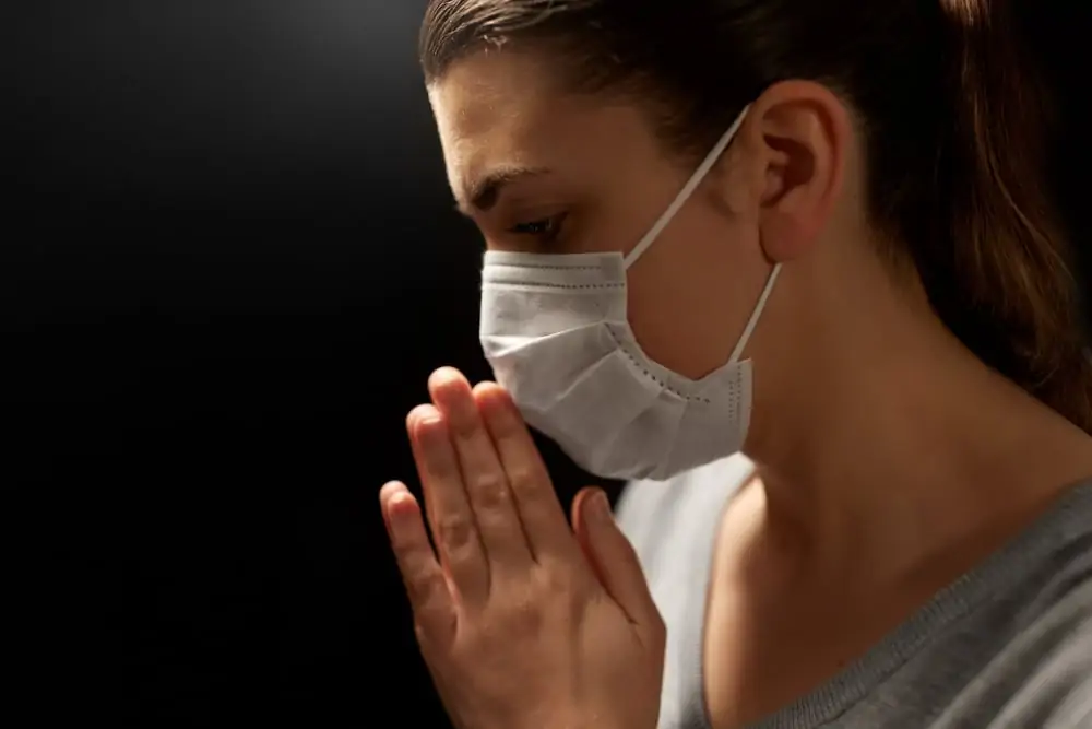 health protection, safety and pandemic concept - close up of sick young woman in protective medical face mask praying over black background;  people prayed for me and my cancer treatment