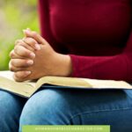 image of woman with folded hands over Bible in cranberry colored sweater for the post how to get closer to God when you don't know where to start