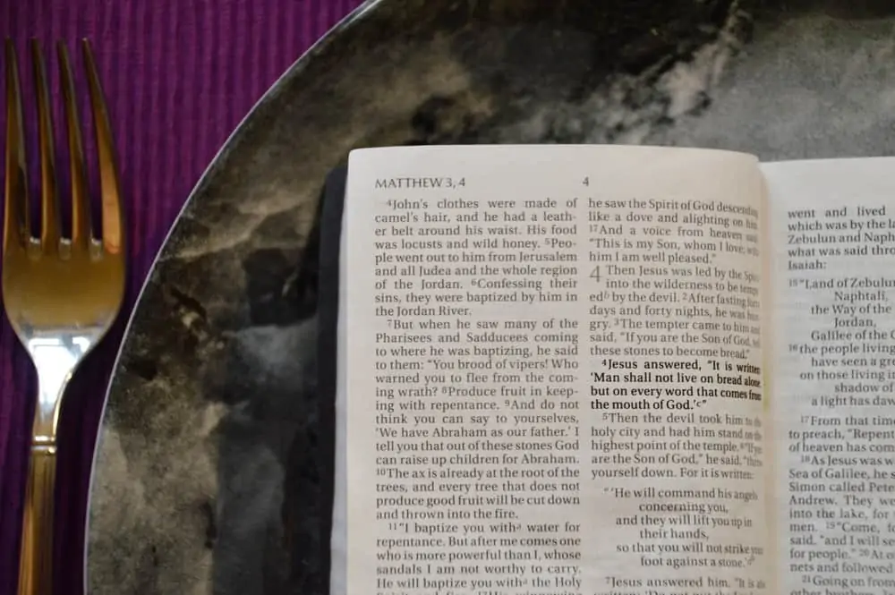 Bible on a dinner plate with silverware in lent, biblical fasting, growing closer to God