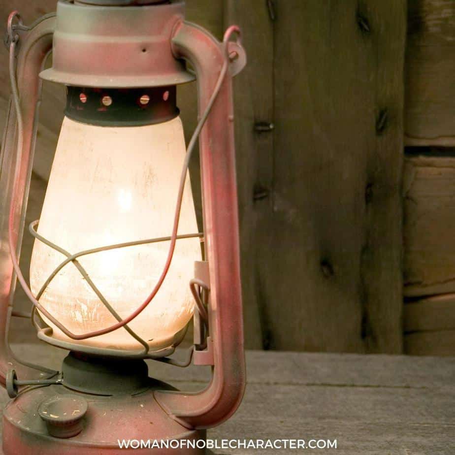 image of worn lantern on wood table for the post Her Lamp Does Not Go Out At Night - What Proverbs 31:18 Really Means