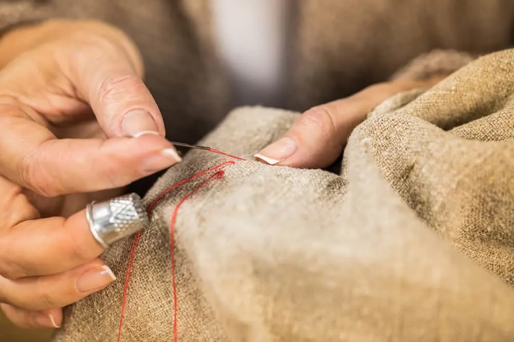 image of woman sewing burlap cloth with red thread for the post: 
