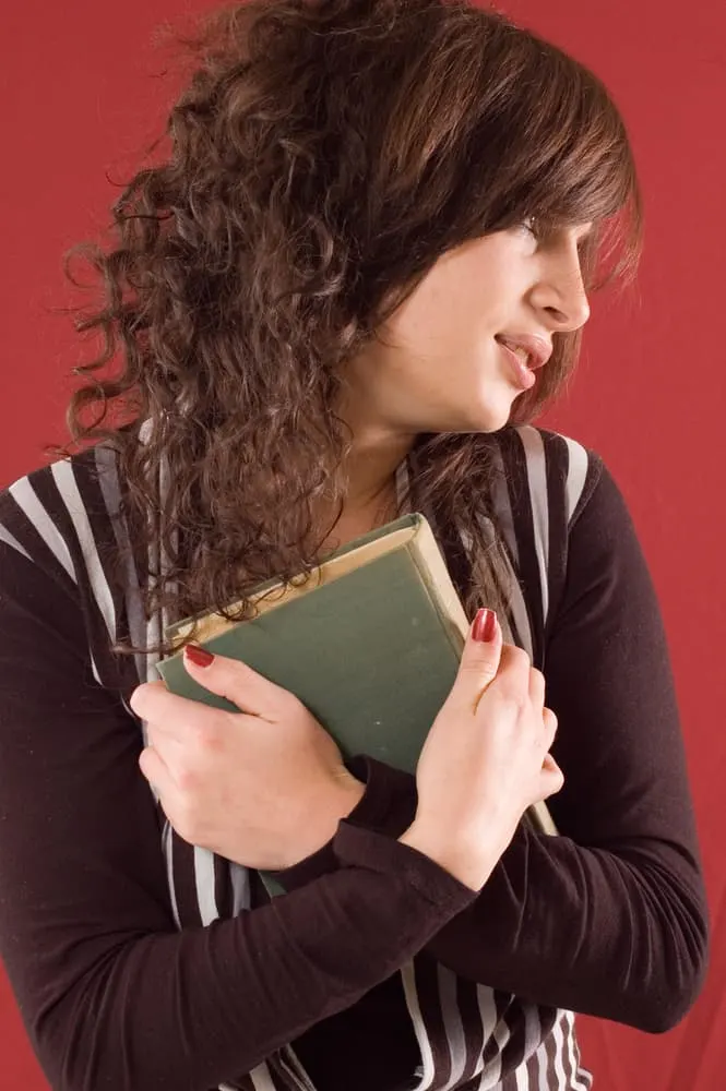 image of Young student girl with books on red backgrounds for the post Beauty is Fleeting, But a Woman Who Fears the Lord is to be Praised