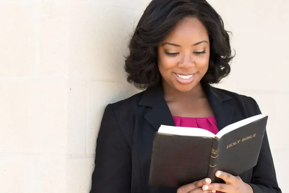 image of woman smiling and reading Bible for the post 15 amazing benefits of reading the Bible