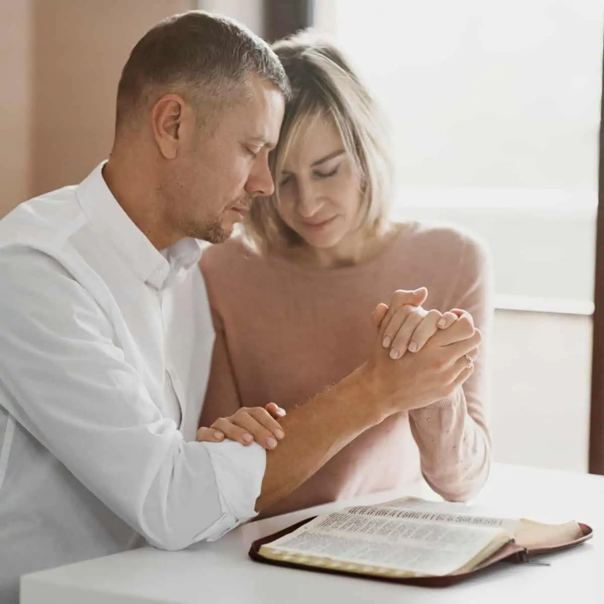 Image of husband and wife praying over the bible for the post how to love your wife as christ loves his church