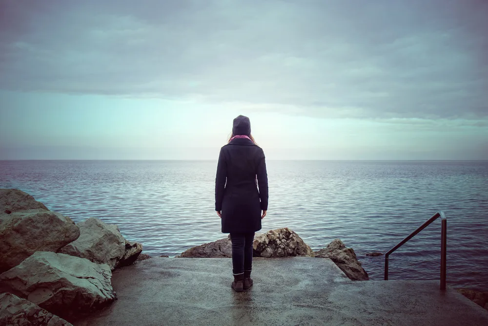 back view of lonely woman looking the see for the post solitude in the Bible