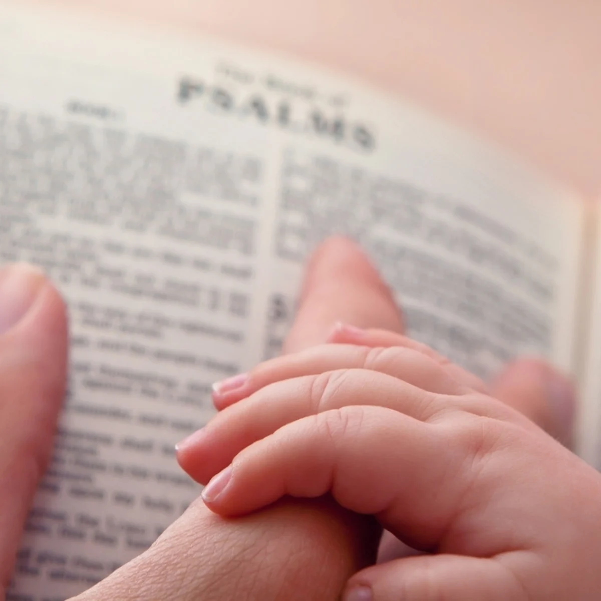 image of baby and mother's hand on Bible for the post balancing discipline and love in Christian parenting